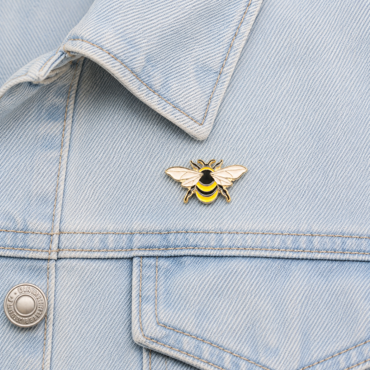 Bumblebee enamel pin on light blue denim near a front pocket seam