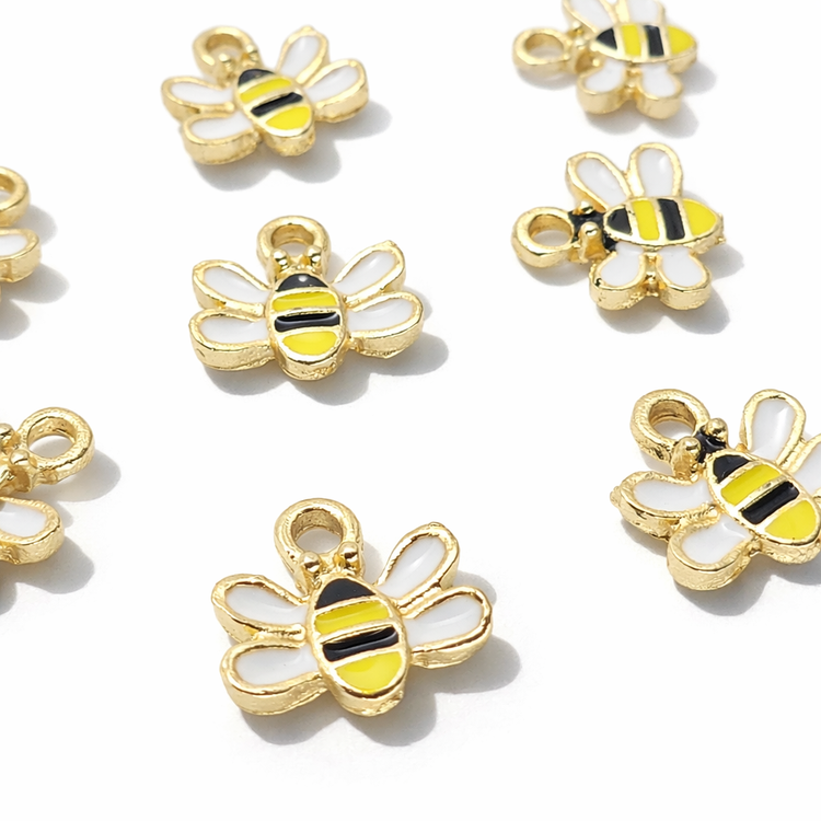 Assorted jewellery-making charms in various styles, including colorful enamel designs and antique-finish Tibetan silver pieces, arranged in a collection for craft and DIY accessories