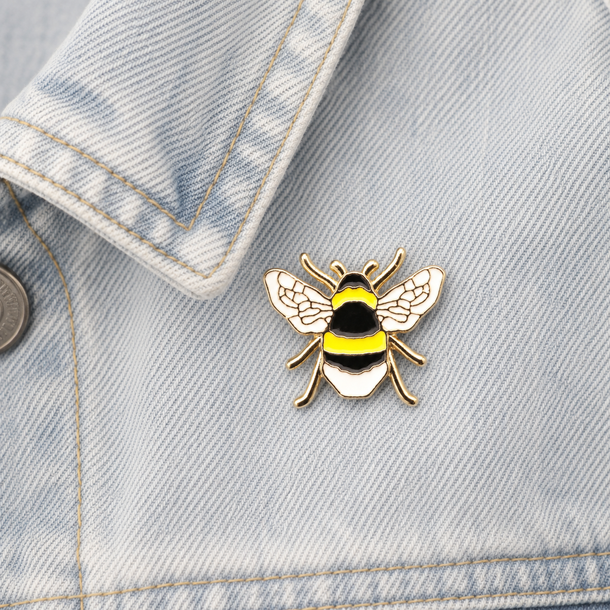 Bee enamel pin on light blue denim jacket front, gold-tone yellow and black