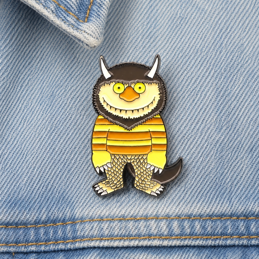 Monster enamel pin badge on blue denim, yellow face and orange striped body