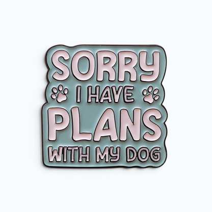 A square enamel pin with a wavy border featuring the text 'SORRY I HAVE PLANS WITH MY DOG' in white letters on a muted blue background, with small paw prints on either side.