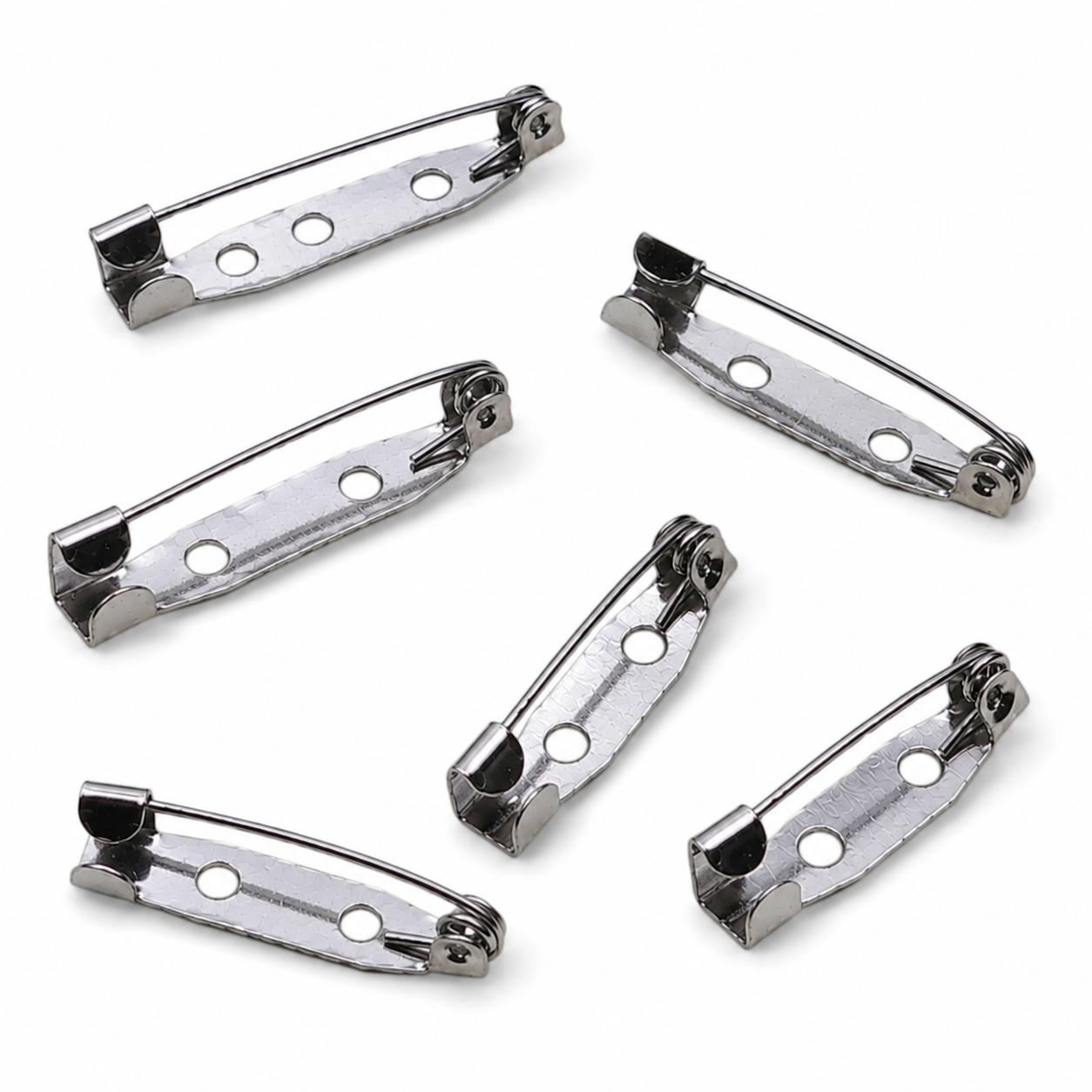 Silver brooch pin backs, angled view of five pieces with hinge clasp and holes