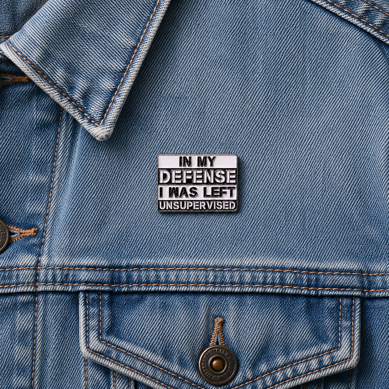 Enamel pin badge on blue denim jacket featuring "IN MY DEFENSE" quote text