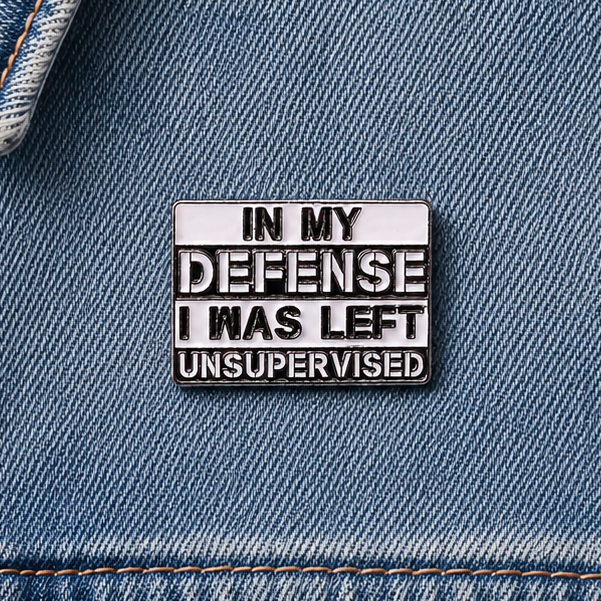 Enamel pin badge on blue denim fabric with "IN MY DEFENSE" quote and silver edges