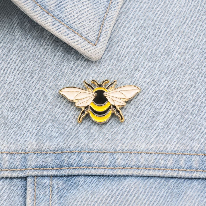 Bumblebee enamel pin on light blue jeans waistband with stitched seams