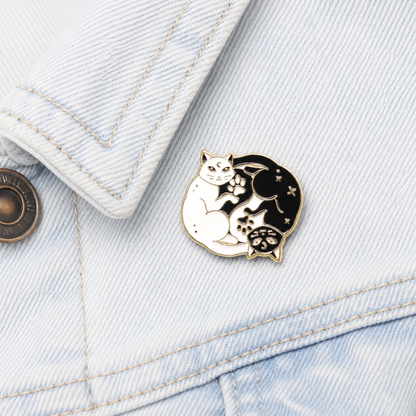 Yin-yang cat enamel pin badge on light blue denim fabric