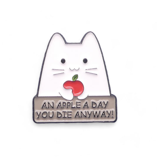 Enamel pin badge with a cat holding an apple and text 'An apple a day you die anyway!' 
