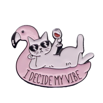 Enamel badge featuring a design with a cat on a pink flamingo with sunglasses and a glass of wine, and the text 'I Decide My Vibe'.
