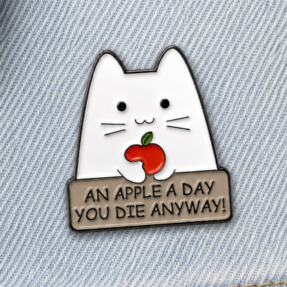 Cat enamel pin badge on light blue denim, white cat with red apple and dark slogan