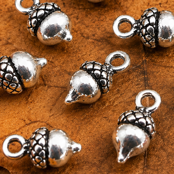 Close-up of tibetan silver acorn charms, glossy metal pendants with loop rings
