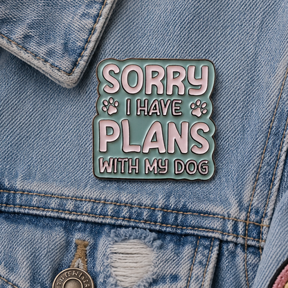 A square enamel pin with a wavy border featuring the text 'SORRY I HAVE PLANS WITH MY DOG' in white letters on a muted blue background, with small paw prints on either side.
