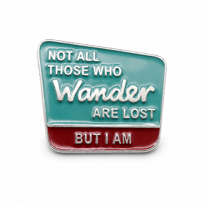 Square enamel pin badge in teal and red with 'Wander' quote text
