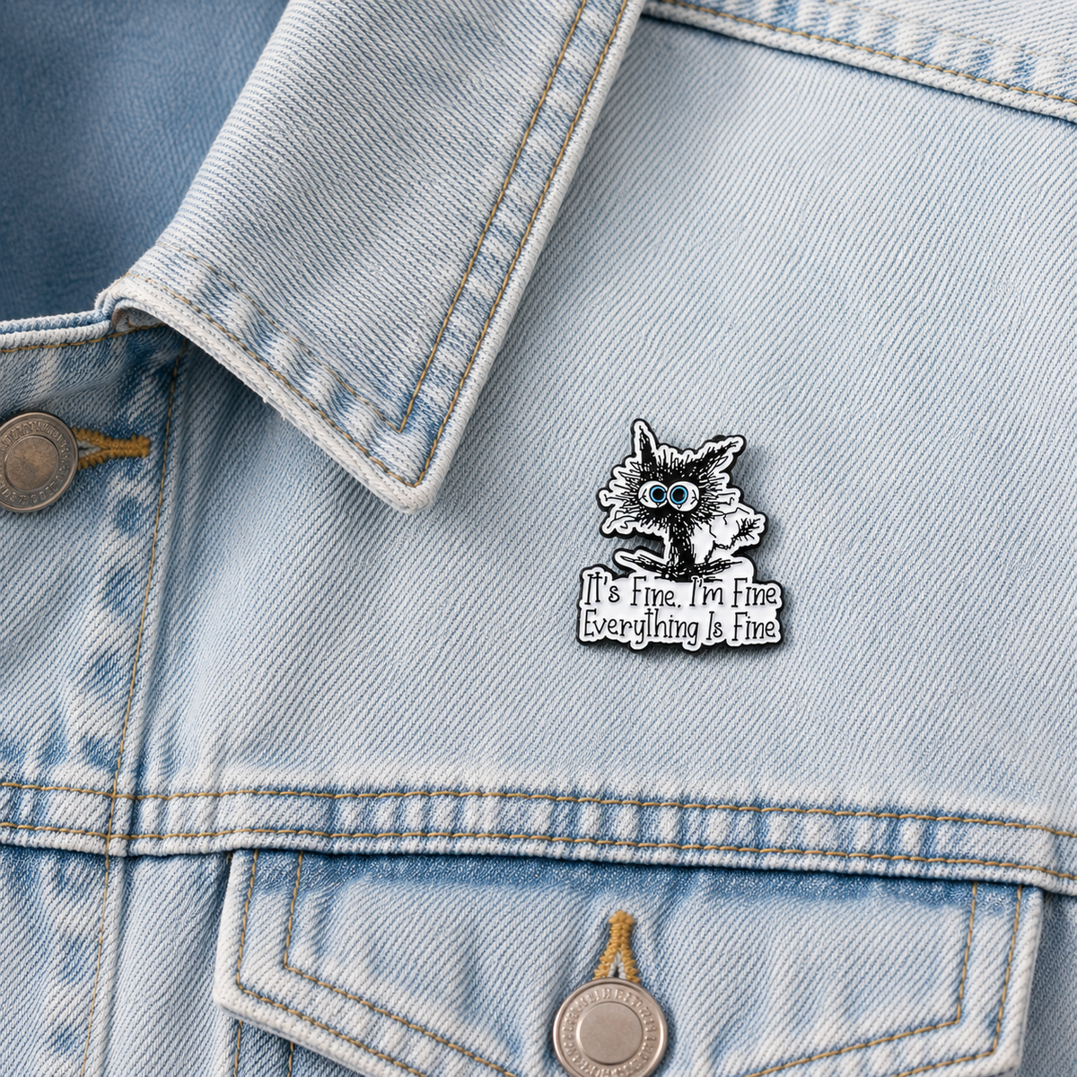 Cat enamel pin badge on light denim, blue-eyed cat with 'It's Fine. I'm Fine Everything Is Fine'