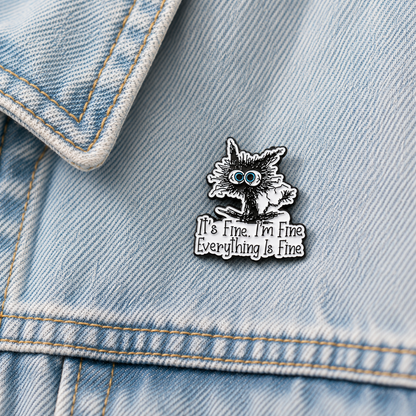 Cat enamel pin badge on light blue denim jacket, blue-eyed cat with 'It's Fine' slogan