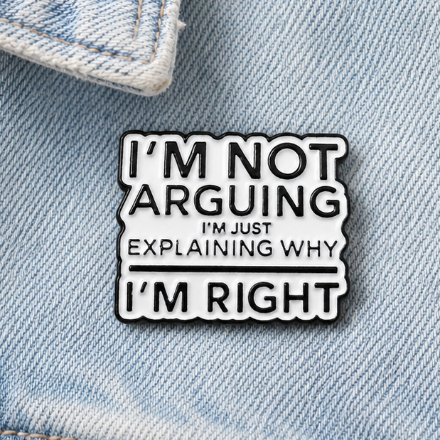 Enamel pin badge close-up with black-and-white quote design and white border