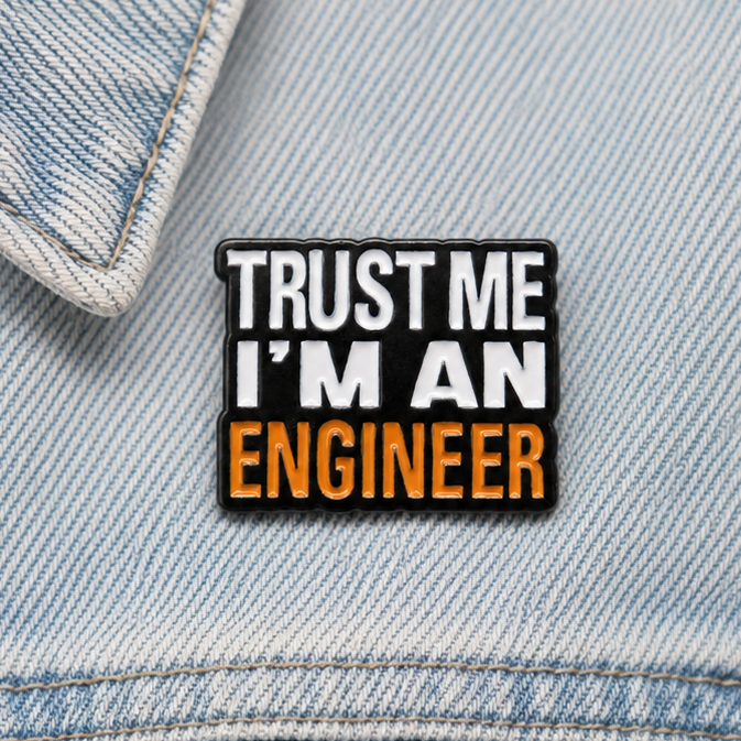 Enamel pin badge “TRUST ME I'M AN ENGINEER” on light blue denim fabric