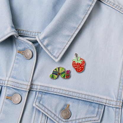 Strawberry and caterpillar enamel pin badges on light blue denim