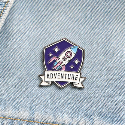 Purple rocket adventure enamel pin badge on light blue denim, close-up front view