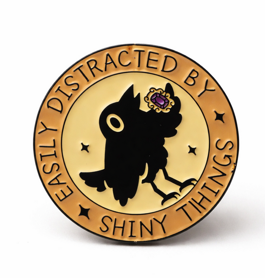 Circular badge pin badge with crow  holding a jewel design and text 'Easily Distracted by Shiny Things' 