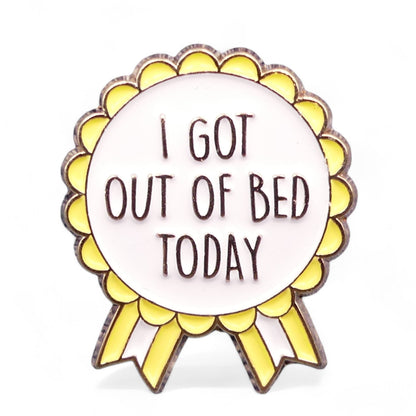 Yellow, White and Gold rosette style enamel pin badge with the text I got out of bed today.
