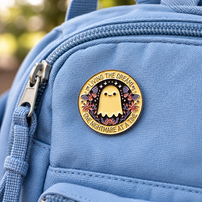 Enamel ghost pin badge with “Living the Dream” on blue backpack pocket