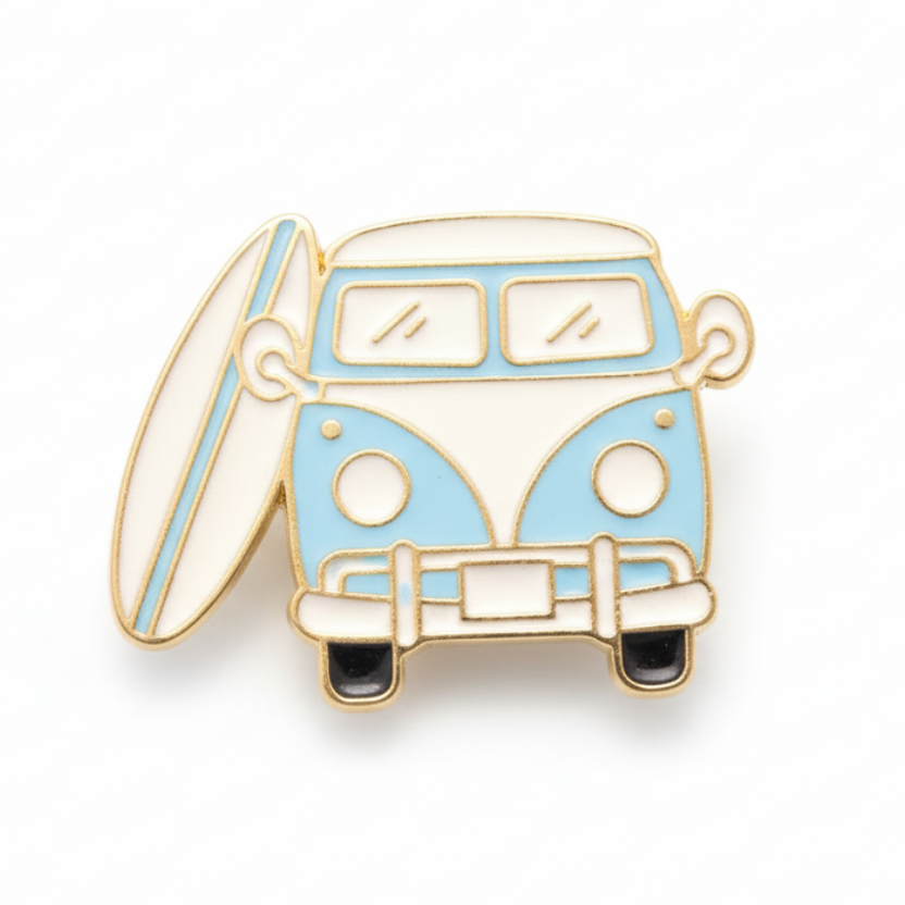 A retro camper van enamel pin badge in blue and white with a surfboard attached to the side.